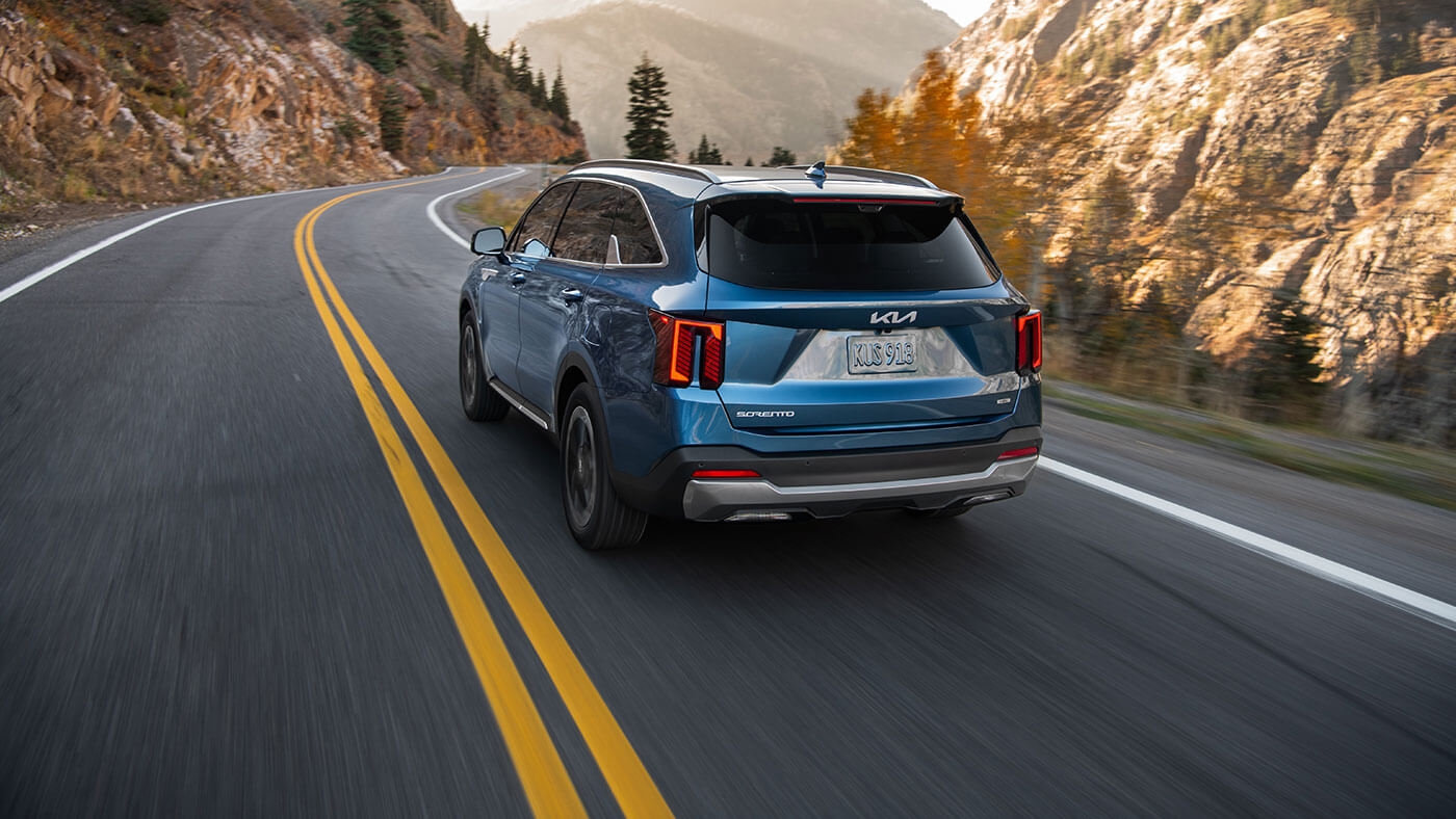 Vue arrière du Kia Sorento HEV 2026 roulant sur un chemin.